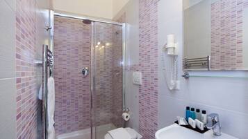 Une salle de bain avec une douche à parois de verre, un lavabo blanc et un miroir au-dessus du lavabo.