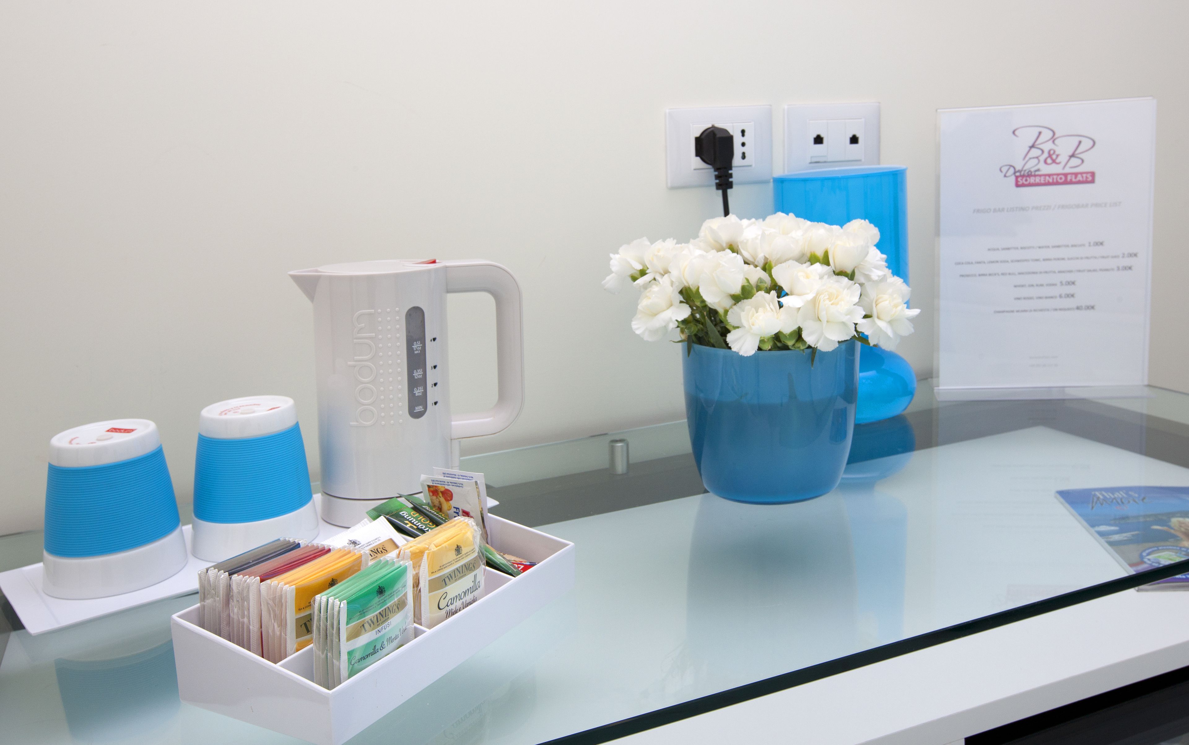 A reception area with a coffee machine, a vase of white flowers, and a display of branded stationery.