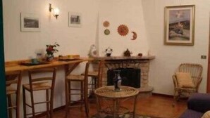 Una sala de estar acogedora con chimenea, una mesa de comedor con sillas y un sillón de mimbre.