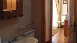 Un baño con lavabo, espejo y armario de madera.