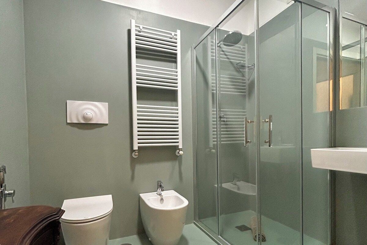 Un baño con cabina de ducha de vidrio, un bidé, un inodoro y un tocador de madera.