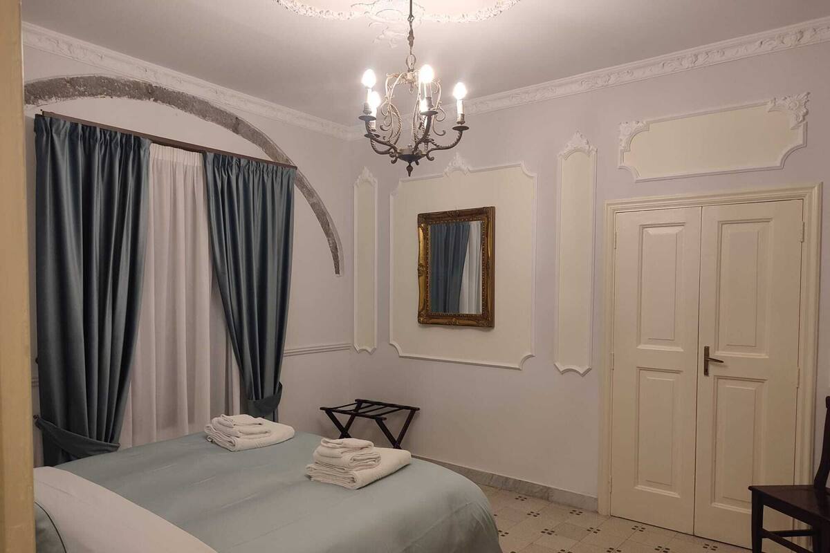 Un dormitorio con cama, candelabro, espejo y armario.