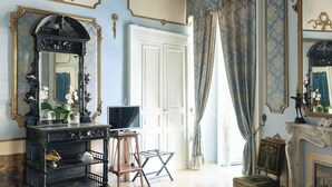 Una habitación con un mueble consola negro, un televisor, una chimenea y un suelo estampado.