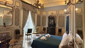 Una habitación con una cama grande, un candelabro, una chimenea y un espejo.
