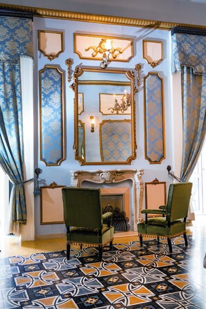 A room with ornate gold-framed mirrors, a fireplace, and two green upholstered chairs. - Carafa di Maddaloni B&B di Charme (Naples)