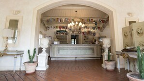 Un espace d’accueil doté d’un comptoir central, de cactus en pot, d’un lustre et d’un mur décoré de différents drapeaux.