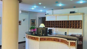 A reception area with a curved counter, a large pillar, and a ceiling with recessed lighting.