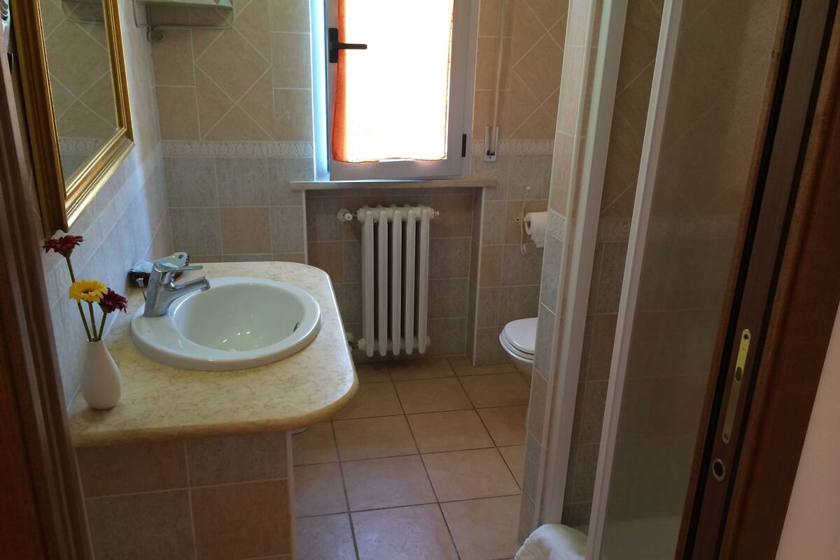 A bathroom with a sink, toilet, and a window.