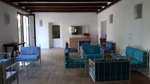 A spacious living area with blue upholstered chairs and a wooden cabinet.