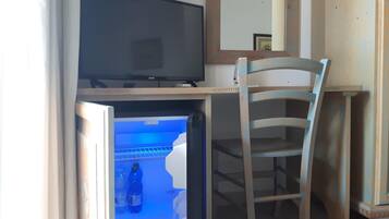 Ein Zimmer mit Fernseher auf einem Schrank, einem Sessel und einem Kühlschrank mit blauer Beleuchtung.