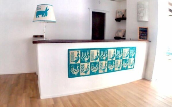 A reception desk with a wooden top and a wall-mounted display of menorahs. - Alghero Vacanze Hotel (Alghero)
