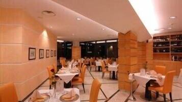 A restaurant with tables set for dining, a bar area, and a wine rack in the background.