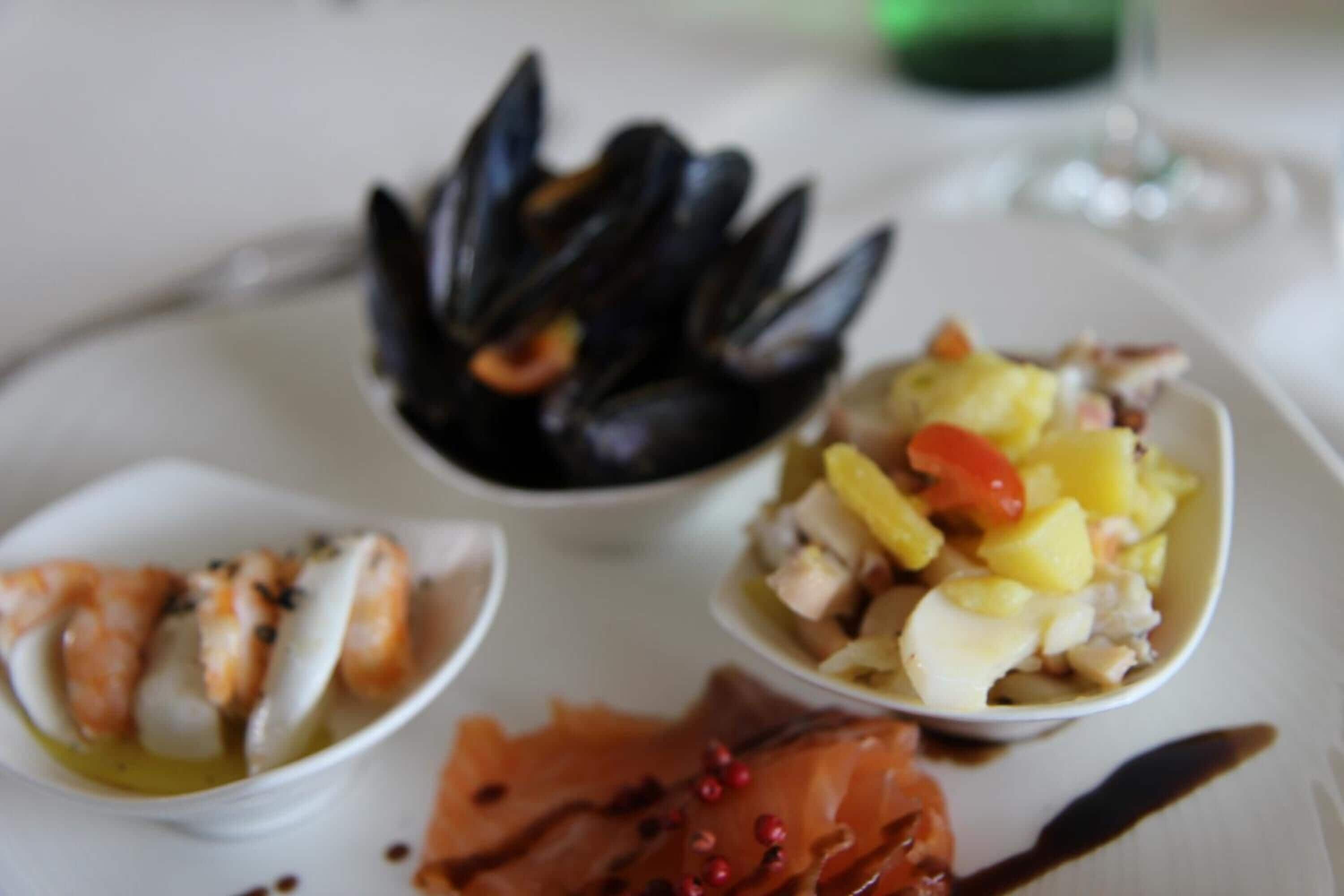 A plate with various seafood dishes including mussels, shrimp, and a mixed seafood salad.