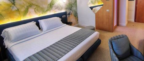 Une chambre d’hôtel avec un grand lit, une chaise et un mur orné d’un motif abstrait original.