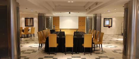 Una sala de conferencias con una mesa grande, sillas y una pantalla de proyección.