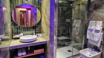 Un baño moderno con un espejo redondo, un lavabo, un bidé y una ducha con mampara de cristal.