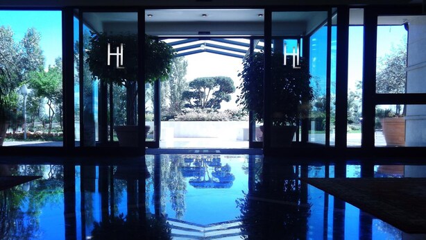A hotel lobby with a reflective pool, large windows, and potted plants. - Hotel Liolá (Castrocielo)
