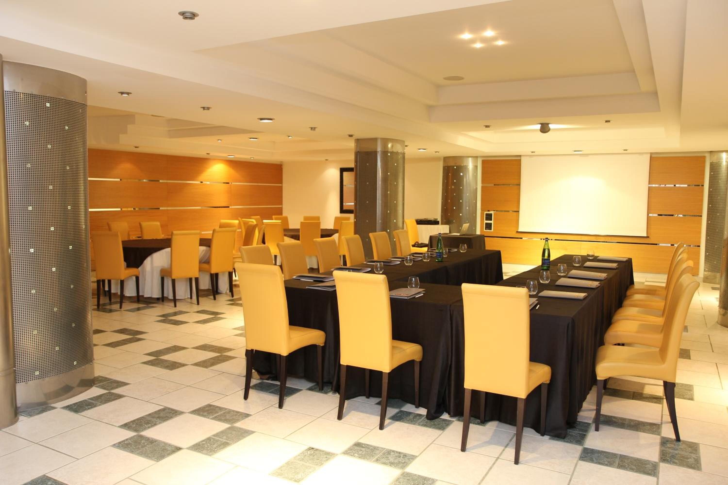 Una sala conferenze con un lungo tavolo, diverse sedie e uno schermo per proiezioni.