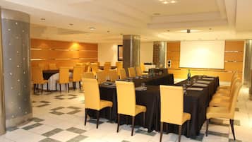 Una sala conferenze con un lungo tavolo, diverse sedie e uno schermo per proiezioni.