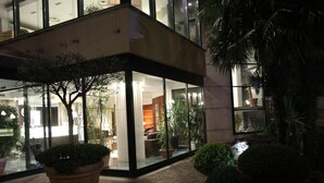 A modern building with a glass facade, large potted plants, and a paved entrance area. - Hotel Liolá (Castrocielo)