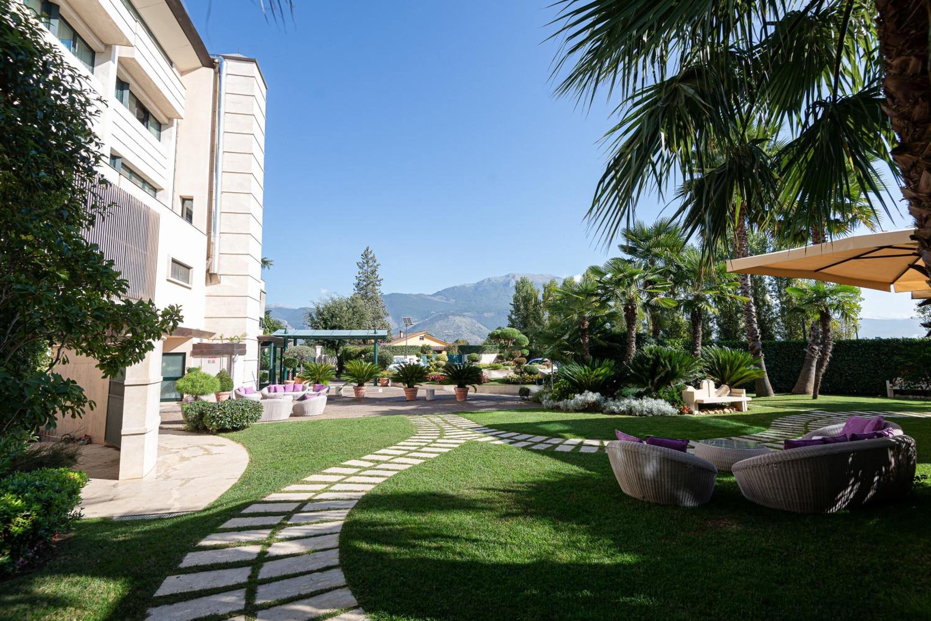 A well-maintained courtyard with a stone pathway, outdoor seating, and lush greenery.