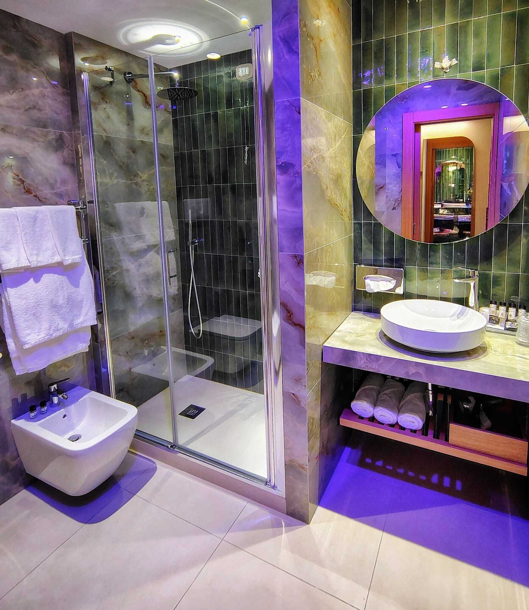 Un baño moderno con ducha envuelta en vidrio, un lavabo blanco y un tocador con espejo.