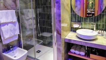 Een moderne badkamer met een douchecabine van glas, een witte wastafel en een badkamermeubel met spiegel.