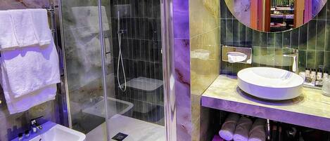 Un baño moderno con ducha envuelta en vidrio, un lavabo blanco y un tocador con espejo.