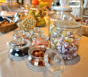 A table with various food items in glass containers, including jars of pickles and a basket of nuts. - Podere Benintendi (Certaldo)