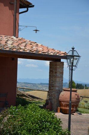 A building with a tiled roof, a brick pillar, and a large terracotta pot. - Podere Benintendi (Certaldo)