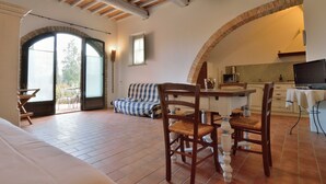 A spacious living area with a dining table, chairs, and a sofa. There is a kitchen area with a stove and a television. - Podere Benintendi (Certaldo)