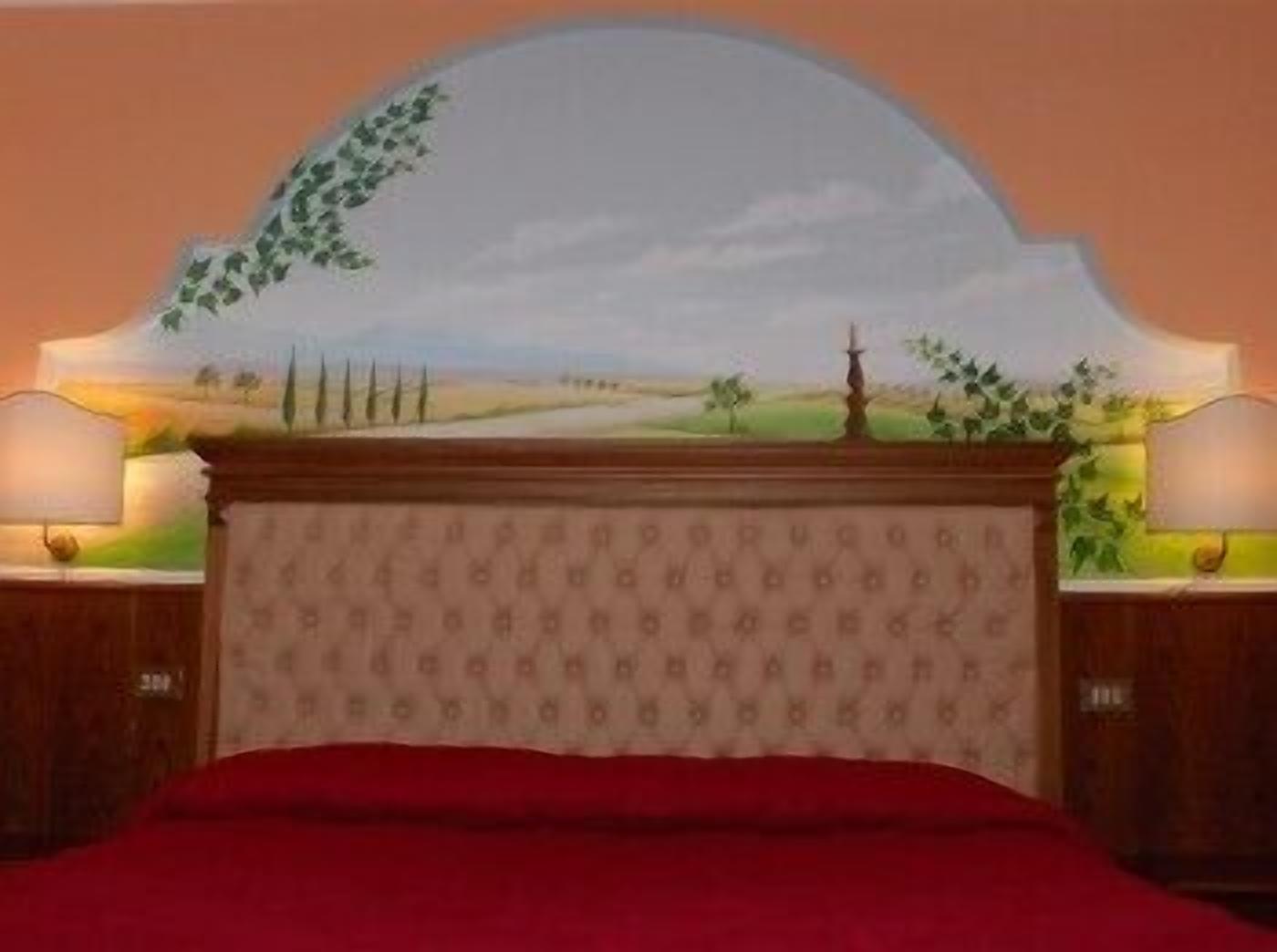 A bedroom with a bed, two bedside tables, and a wall mural.
