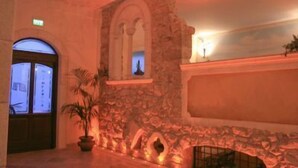 A stone fireplace with a mantel, a potted plant, and a doorway with an arched design. - Marchesina Resort (Teggiano)