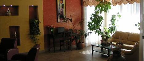 A living room with a sofa, chairs, a coffee table, and potted plants.
