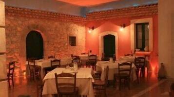 A restaurant with stone walls, multiple tables, and chairs.