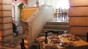 A dining area with a table set for a meal, a staircase, and a view of a stone wall. - Marchesina Resort (Teggiano)