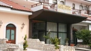 A hotel with a sign reading "Marcheginas." It features a stone facade, a red-tiled roof, and a balcony with railings. - Marchesina Resort (Teggiano)
