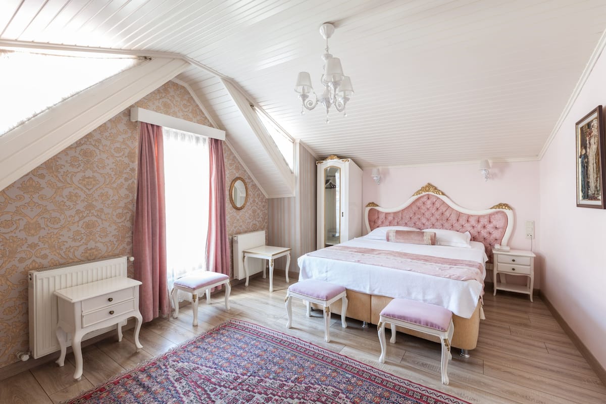 A bedroom with a large bed, a dresser, a mirror, and a radiator.