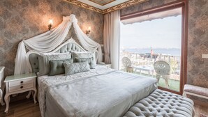 Un dormitorio con cama con dosel, vista a la ciudad y balcón con mobiliario exterior.