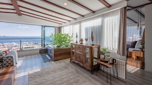 Un salón amplio con un gran ventanal con vistas al mar, un aparador de madera y una zona de estar acogedora.
