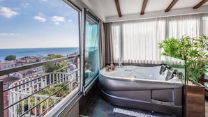 Un baño moderno con una bañera grande, un box de ducha de vidrio y vistas a la ciudad.