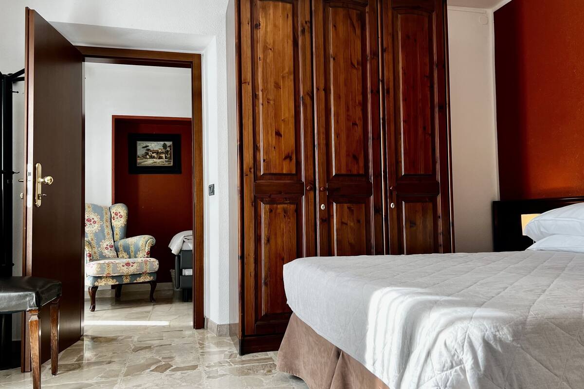 Une chambre d’hôtel avec un lit, une armoire en bois, une chaise et un bureau.