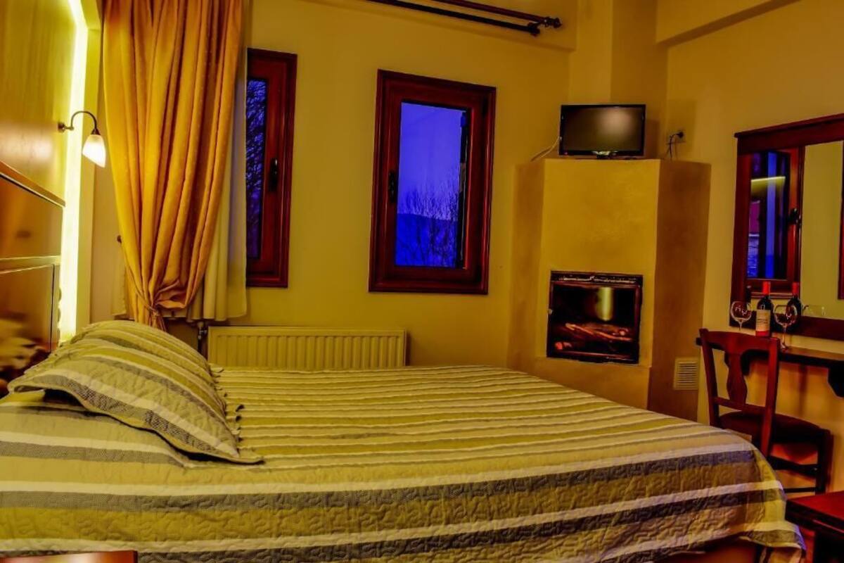 A room with a bed, a television, a fireplace, and a window with a view.