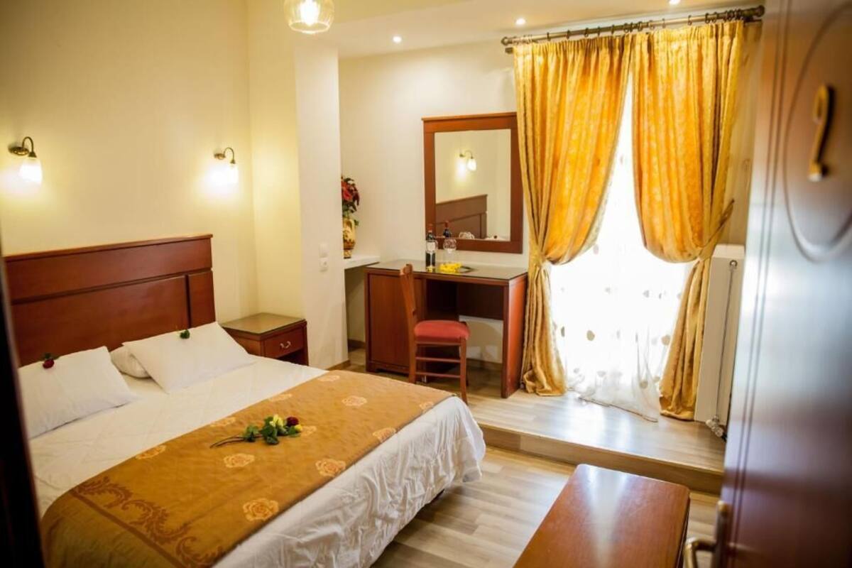 A hotel room with a bed, bedside table, desk, chair, and a mirror.