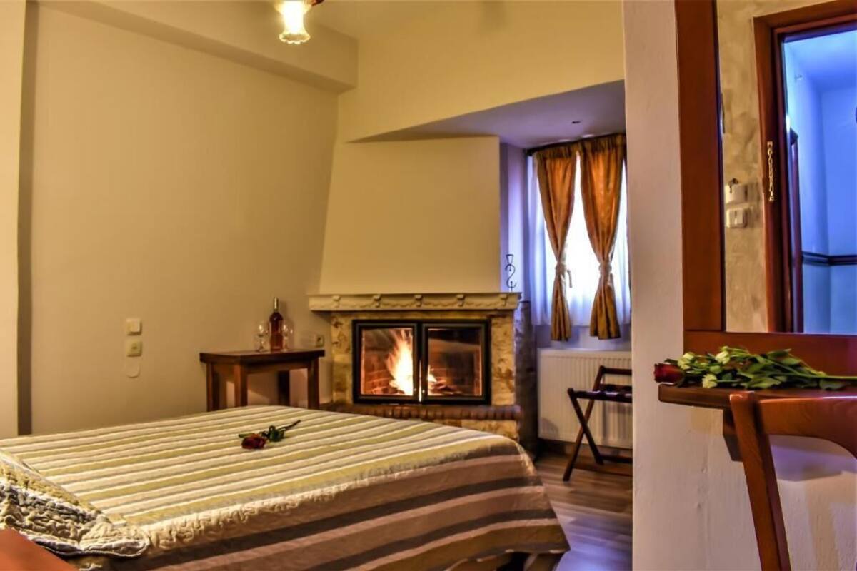 A bedroom with a bed, a fireplace, a window with curtains, and a chair.