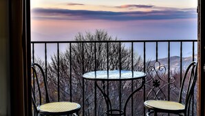 Un balcón con dos sillas y una mesa, con vistas a un paisaje montañoso.