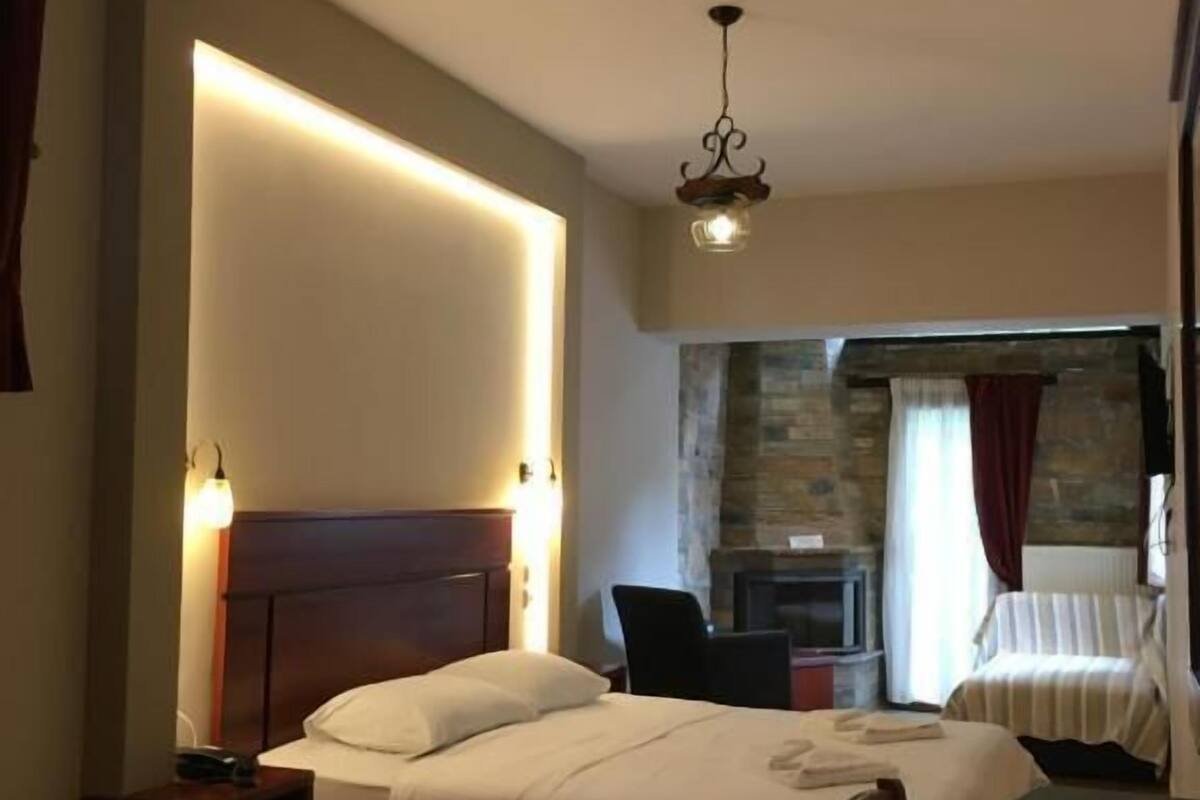 A hotel room with a bed, bedside table, chair, and a small table with a chair.