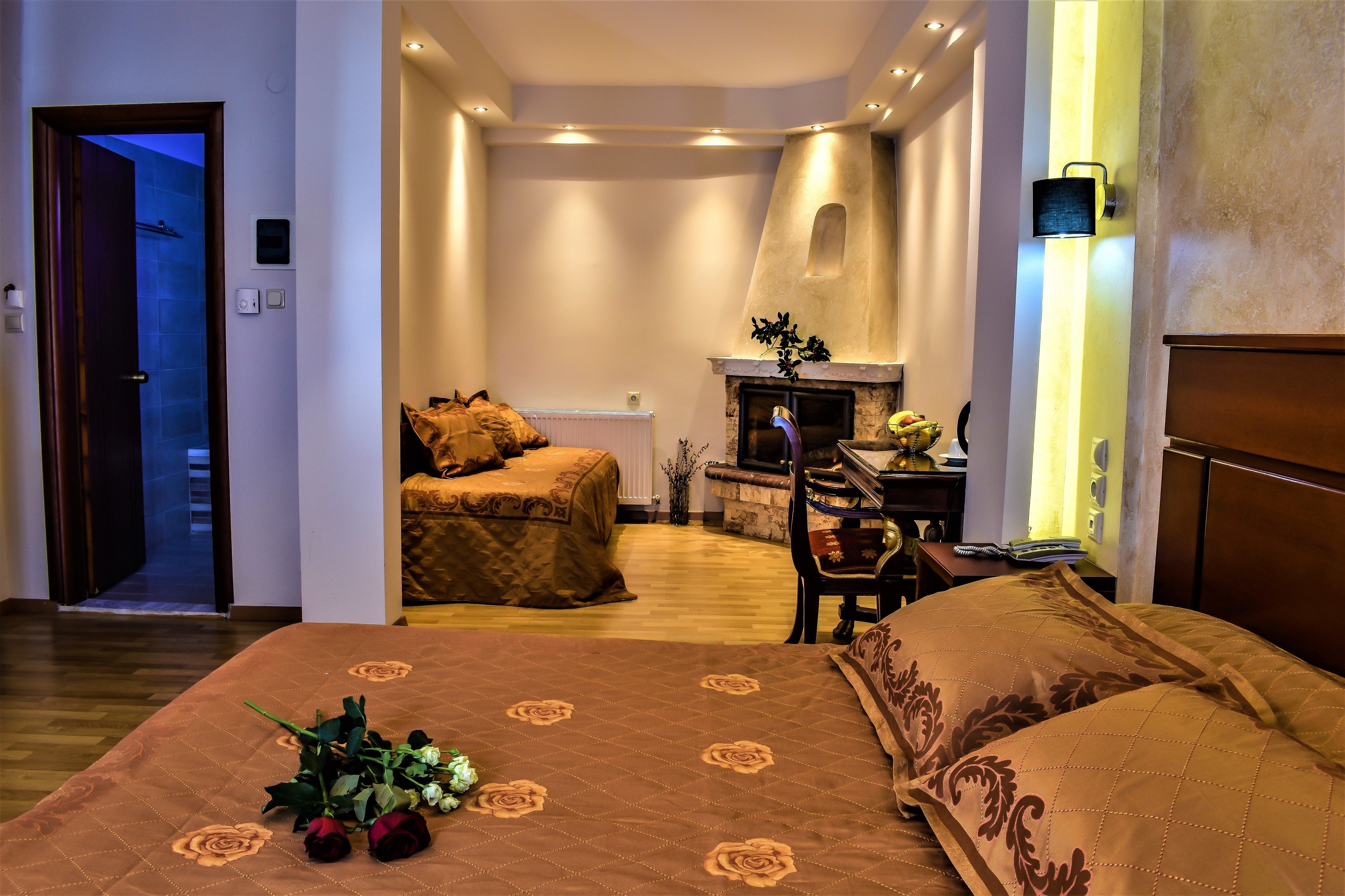 Habitación de hotel con una cama grande, zona de estar con chimenea y vistas al pasillo.