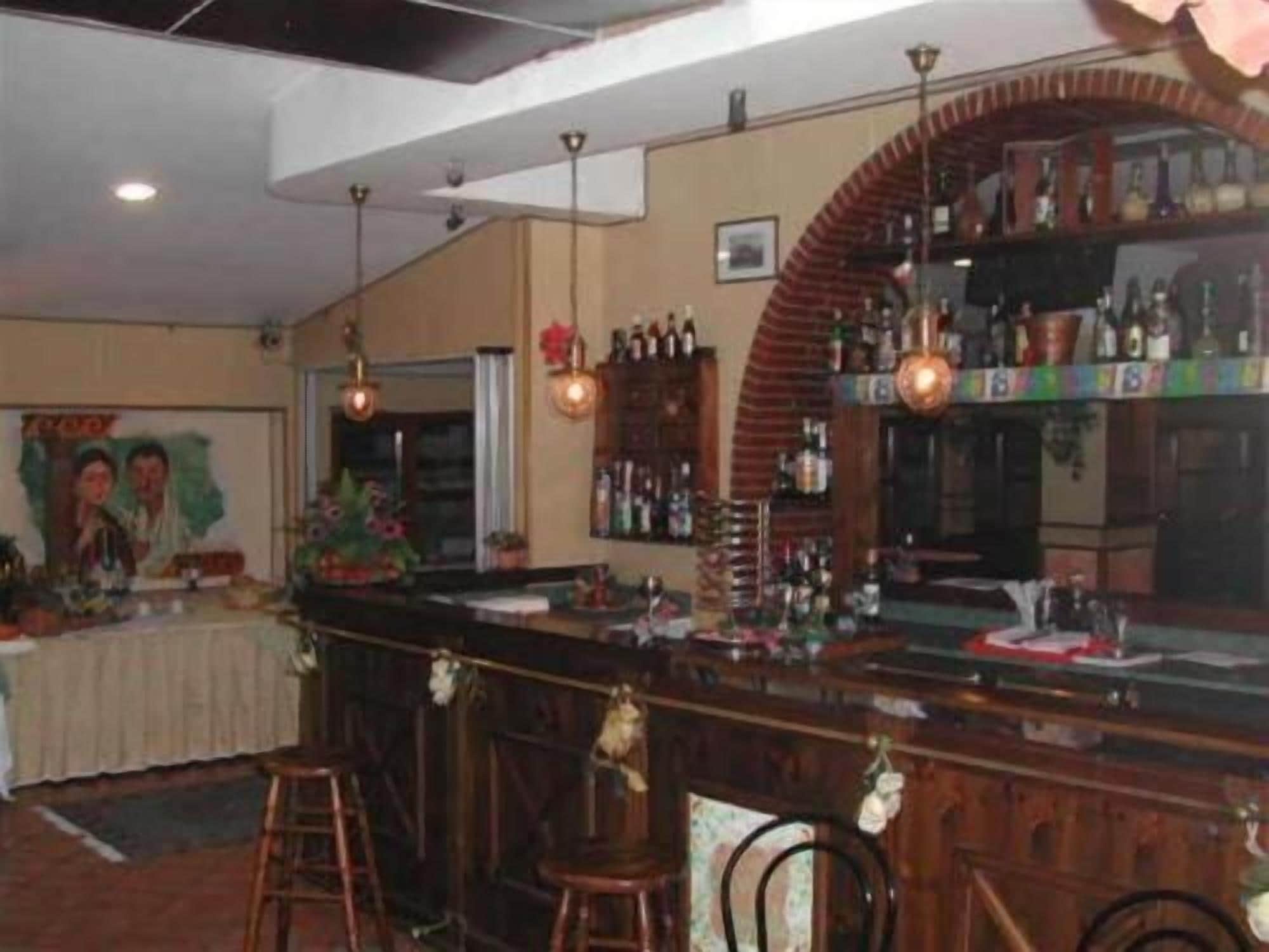 Un'area bar con sgabelli, un bancone e una selezione di bottiglie.