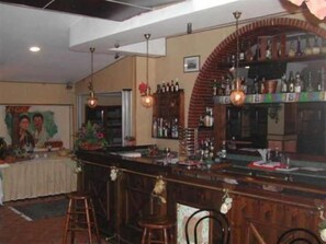 Zona de bar con taburetes, mostrador y una variedad de botellas.